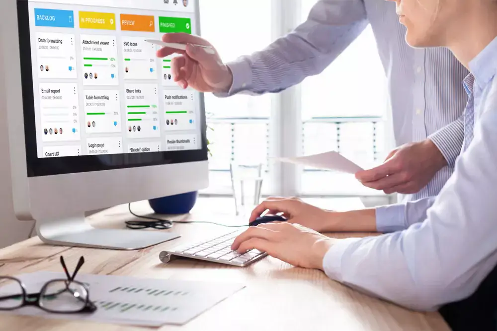 A team looking at a dashboard on a monitor and discussing a project