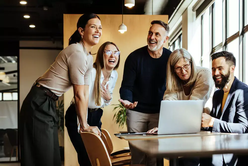 Happy businesspeople laughing while collaborating on a new project in a modern office.